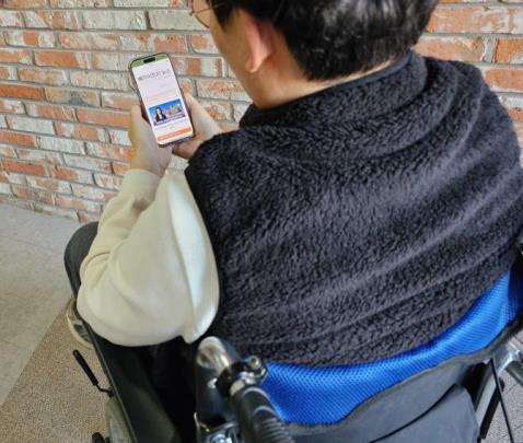 휴대폰으로 디지털 정보신문을 보고 있는 장애인 구독자의 모습. <사진=관악구>