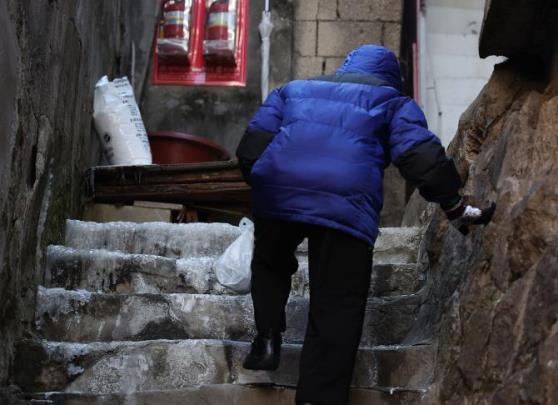 얼음이 언 계단을 힘겹게 오르는 한 어르신 <자료사진=연합뉴스>